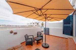 eine Terrasse mit einem Tisch, Stühlen und einem Sonnenschirm in der Unterkunft Casa Any Lanzarote in Playa Honda