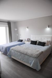 a white bedroom with two beds and a window at Sesimbra Oasis Apartment in Sesimbra