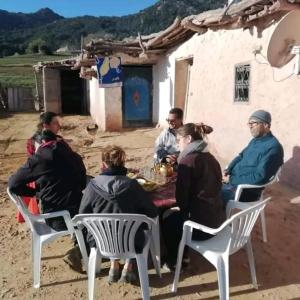 a group of people sitting around a table in front of a house at Gite Ain Bechar in Taza