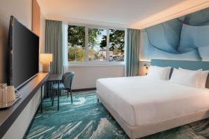 布吉瓦尔DoubleTree by Hilton Paris Bougival的一间带床、书桌和电视的酒店房间