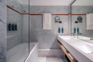 a bathroom with two sinks and a tub and a shower at DoubleTree by Hilton Paris Bougival in Bougival