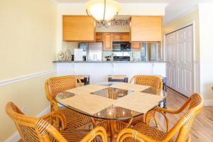 Un comedor con mesa y sillas y una cocina. en Oceanfront Condo with pool - Walk to the Tiki Bar, en Carolina Beach