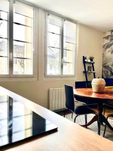 ein Esszimmer mit einem Tisch, Stühlen und Fenstern in der Unterkunft Eden Blue charmant appartement proche centre avec Garage Gratuit in Nantes