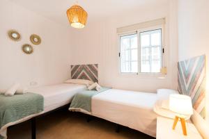 two beds in a room with a window at Victoria Square 2, Center Apartment in Málaga