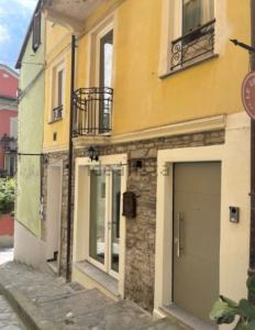 a yellow building with a garage on a street at La Quintessenza del Borgo in Varzi