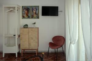 uma sala de estar com uma cadeira e uma televisão na parede em Casa Graziosa em Ercolano