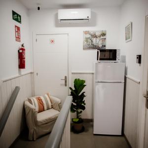 Habitación pequeña con nevera blanca y silla en Pensión Mastil 16, en Málaga