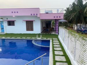 una casa rosa con piscina frente a ella en Royal Experience Pink Breeze Villa, Kuvathur ECR Highway Chennai, en Kūvattūr