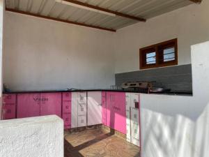 cocina con encimera y paredes de color rosa y blanco en Royal Experience Pink Breeze Villa, Kuvathur ECR Highway Chennai, en Kūvattūr