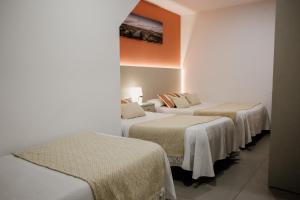 um grupo de camas num quarto com paredes brancas em Pensión Mastil 16 em Málaga
