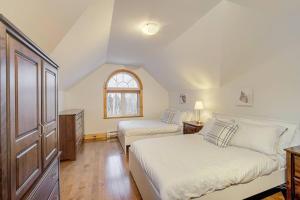 een slaapkamer met 2 bedden en een raam bij Idyllic Nature Retreat - Hot tub and Scenic Views in Baie-Saint-Paul