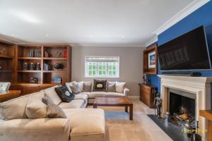 a living room with a couch and a fireplace at Luxe Home with Hot Tub, Cinema, Games Room & Sauna in Buckinghamshire