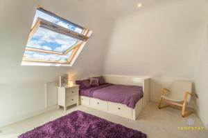 1 dormitorio con cama morada y ventana en Luxe Home with Hot Tub, Cinema, Games Room & Sauna en Buckinghamshire