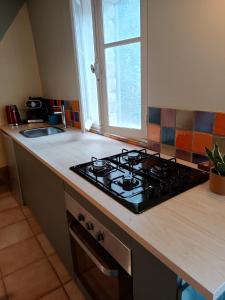 un comptoir de cuisine avec une cuisinière et une fenêtre dans l'établissement Sous la vigne, à Rustrel