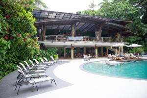 a resort with chairs and a swimming pool and a building at Pachira Lodge in Tortuguero