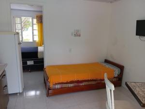 - une chambre avec un lit et une couverture orange dans l'établissement Casas Amarelas Ingleses, à Florianópolis