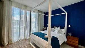 1 dormitorio con cama con dosel y paredes azules en Villa familiale avec piscine en Tamarin