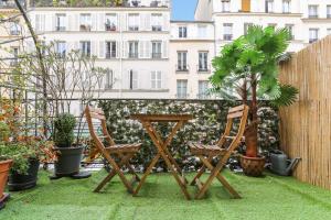 two chairs and a table and a palm tree on a patio at 253 Suite Martinez - Superb apartment in Paris in Paris