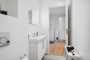 a white bathroom with a sink and a mirror at Moderne Lejlighed i Aalborg Vestby - 1 BR in Aalborg