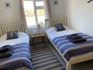 two twin beds in a room with a window at Beachside, Torcross, between the Sea and the Ley in Torcross +29 photos