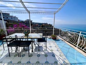 balcón con mesa, sillas y vistas al océano en Bella Tropea Suite, en Tropea