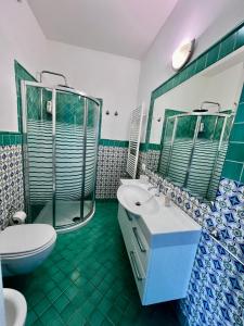 トロペアにあるBella Tropea Suiteの緑と白のバスルーム(トイレ、シンク付)