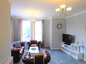 a living room with couches and a tv at City Centre 2 bedroom apt, close to M8 & Tourist Attractions in Glasgow