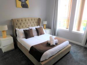 a bedroom with a large bed with white sheets and pillows at City Centre 2 bedroom apt, close to M8 & Tourist Attractions in Glasgow