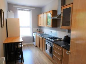 a kitchen with wooden cabinets and a stove top oven at City Centre 2 bedroom apt, close to M8 & Tourist Attractions in Glasgow