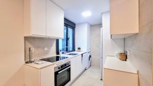 uma cozinha com armários brancos e um forno com placa de fogão em Apartamento Rompeolas em Llanes