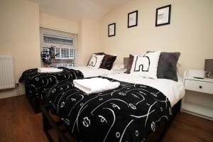 two beds with black and white sheets in a bedroom at Llareggub by StayStaycations in Port Talbot