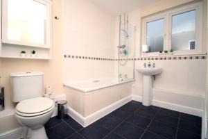 a white bathroom with a toilet and a sink at Llareggub by StayStaycations in Port Talbot