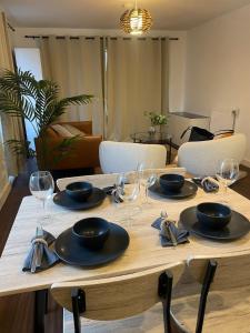 a wooden table with plates and wine glasses on it at Superior Cambridge 2 Bed Apartment inc King Bed in Trumpington