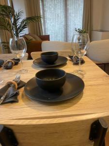 una mesa de madera con dos tazones y copas de vino en Superior Cambridge 2 Bed Apartment inc King Bed, en Trumpington
