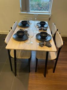 una mesa de madera con sillas y copas de vino en Superior Cambridge 2 Bed Apartment inc King Bed, en Trumpington