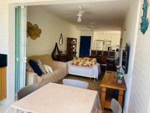 uma sala de estar com um sofá e uma mesa em Apto com ar-cond e piscina a 100 m praia da Enseada em Ubatuba