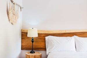 Bett mit einem Kopfteil aus Holz und einer Lampe in der Unterkunft OPacifico Hotel Boutique in Naranjo