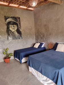 a bedroom with two beds and a painting on the wall at Pousada Kiarô Caraíva in Caraíva
