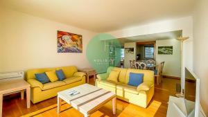 una sala de estar con 2 sofás amarillos y una mesa. en YES Vista Marina T1 by HsR Vilamarina, en Quarteira
