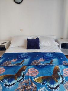 ein Bett mit einer Tagesdecke mit Schmetterlingen darauf in der Unterkunft Apartmani Vesna in Pag