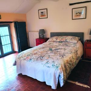 a bedroom with a bed with a floral bedspread at Le Ptit Cottage in Nyons