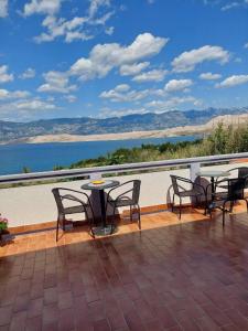 a patio with tables and chairs and a view of the water at Apartmani Vesna in Pag