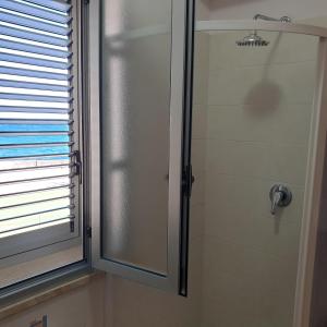 eine Dusche mit einer Glastür neben einem Fenster in der Unterkunft Rising Sun Bay in Augusta