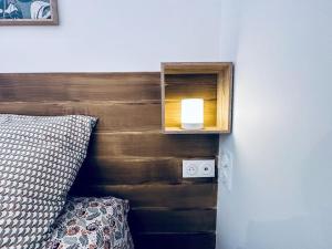 a bed with a wooden headboard with a light on it at Le Héron - Élégance - Confort moderne - 2RFHomes in Château-Thierry