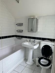 a bathroom with a toilet and a sink and a tub at Eva Suites in Gillingham