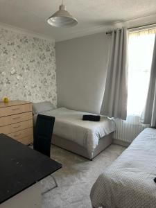 a bedroom with two beds and a desk and a window at Eva Suites in Gillingham