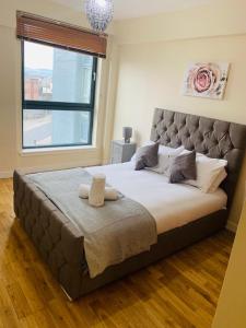 1 cama grande en un dormitorio con ventana grande en Modern 2 Bed Apartment, Close to Gla Airport & M8 en Paisley