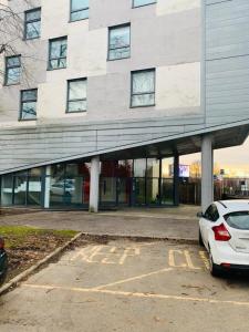 a white car parked in a parking lot in front of a building at Modern 2 Bed Apartment, Close to Gla Airport & M8 in Paisley