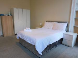 een slaapkamer met een groot bed met witte lakens bij Comfortable 4 bed Apt in Paisley Next to Station in Paisley