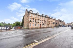 una calle vacía frente a un gran edificio en Comfortable 4 bed Apt in Paisley Next to Station, en Paisley